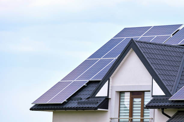Residential house with rooftop covered with solar photovoltaic panels for producing of clean ecological electrical energy in suburban rural area. Concept of autonomous home.